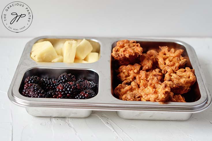 A side view of these mac and cheese bites in a bento box lunchbox.