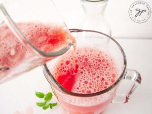 Mixing the blended fruit with remaining water in a large pitcher.