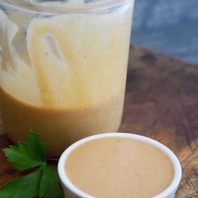 A finished jar of Chick Fil A Sauce sits with a small additional dish of sauce next to it, just served and ready to enjoy.