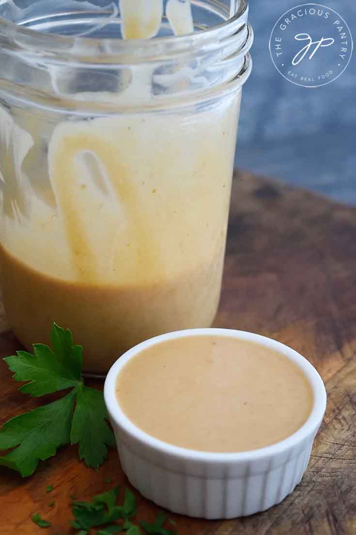 A finished jar of homemade Chick Fil A Sauce sits with a small additional dish of sauce next to it, just served and ready to enjoy.