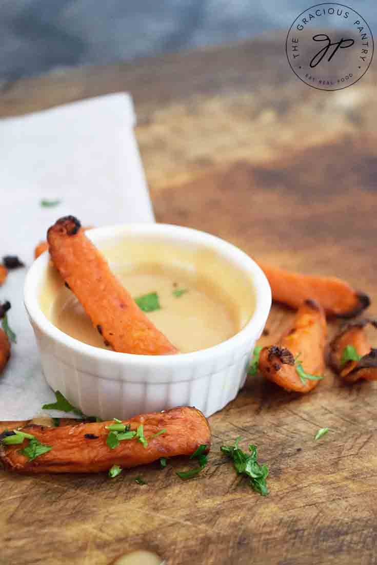 A side view of a small dish of this sauce with sweet potato fries scattered around it.