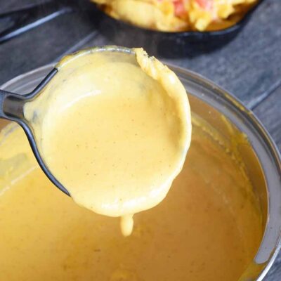 Delicious Nacho Cheese Sauce being ladled out of the pot and onto some corn chips.