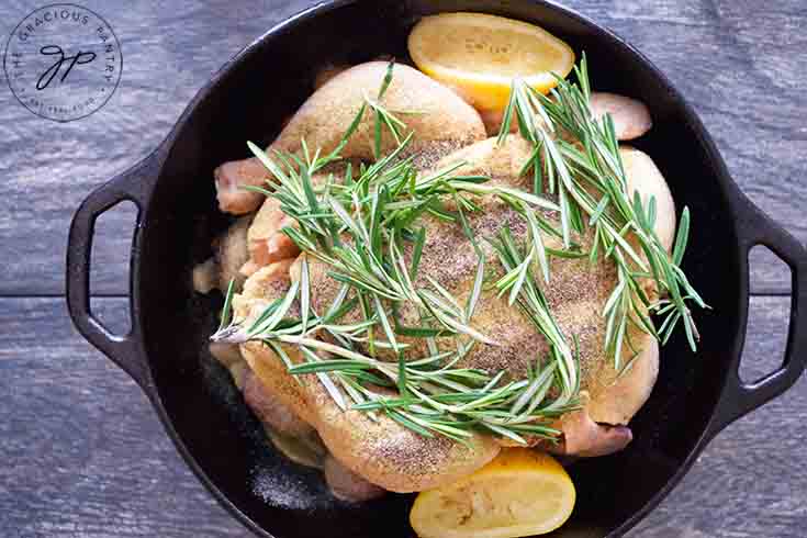 Fresh rosemary sprigs laid over the top of the dutch oven chicken.