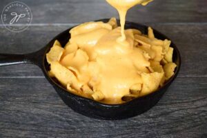 Nacho Cheese Sauce drizzling over the waiting chips.