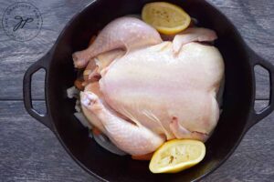 Used lemon halves sit, tucked in on each side of the chicken after the juice has been hand squeezed over the bird.