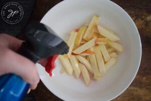 Step 4 - Spritz your apple fries with an oil sprayer and toss.