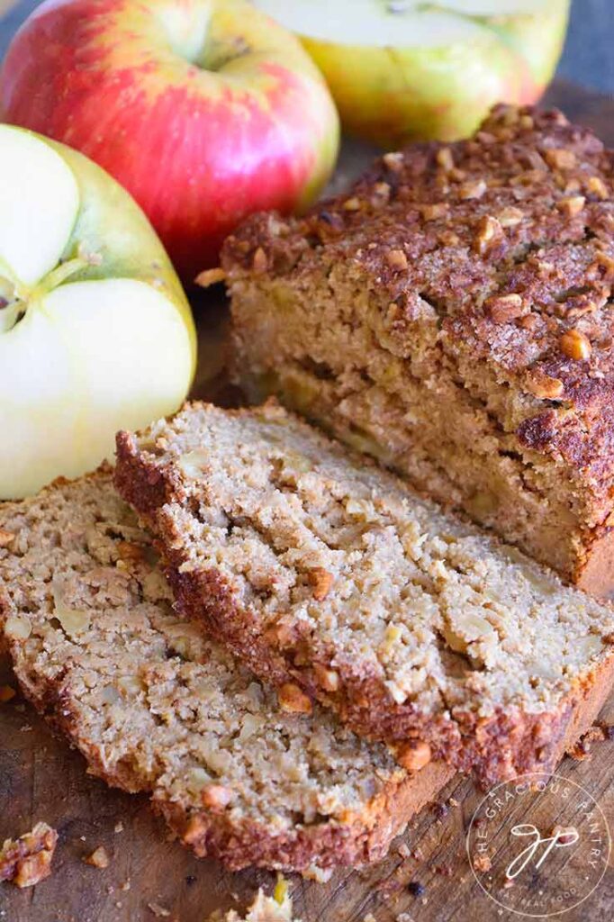 Healthy apple Bread sliced on a cutting board next to some apples.