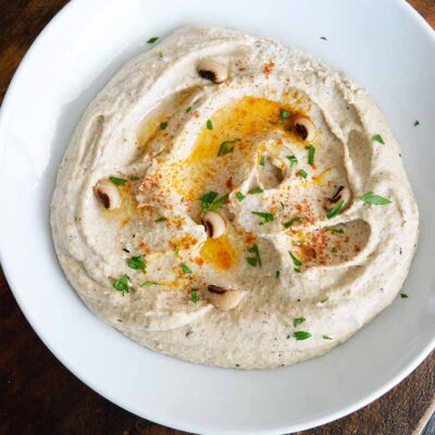 Overhead shot of a serving bowl with Black Eyed Pea Hummus being served at the table.