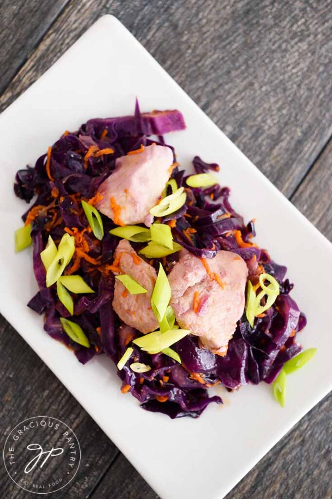 Overhead view of this chicken and cabbage on a white plate.