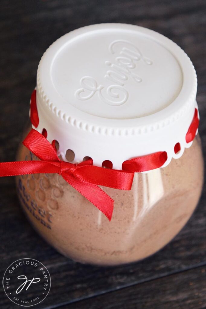 Mug cake mix in a closed jar. A red ribbon laces around the exterior of the lid like a gift.