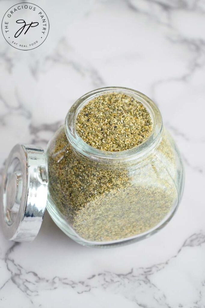 A clean jar filled with Ranch Dressing Mix, it's lid propped agains the side of the jar.