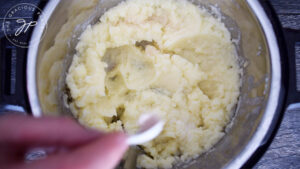 Adding salt to taste to the mashed potatoes.
