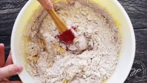 Combining wet and dry ingredients in large mixing bowl.