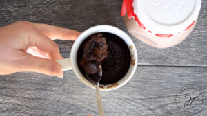 Taking a chunk of cake out of the mug with a fork.