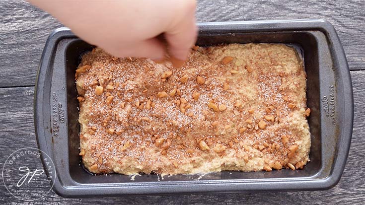 Sprinkling toppings over the unbaked apple bread.