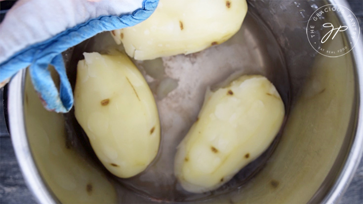 Draining the water off the cooked potatoes.