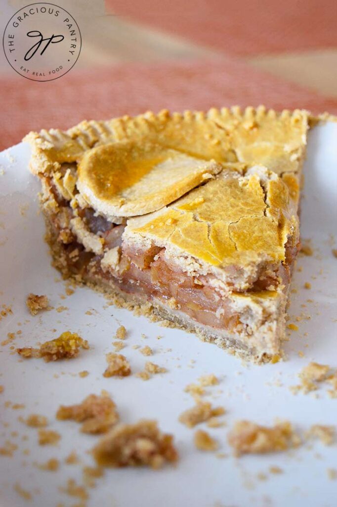 A side view of this single slice of apple pie in a white pie plate.