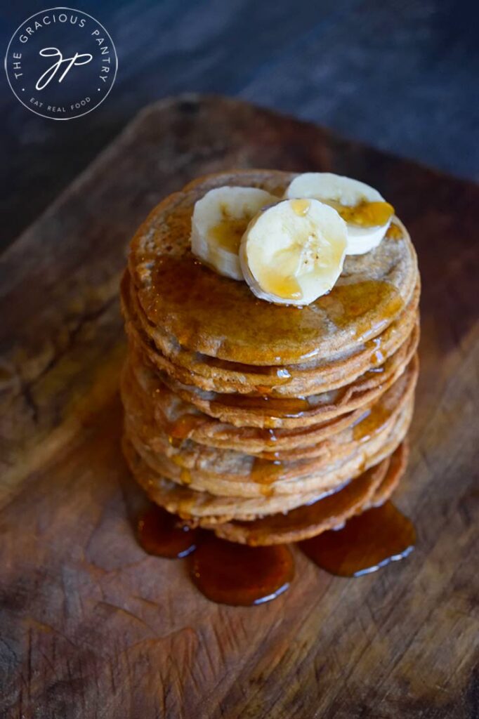 An overhead view of these banana pancakes covered in banana slices and maple syrup.