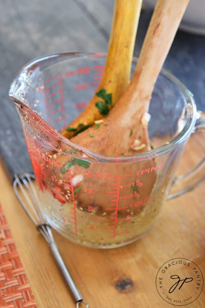 Measuring cup holding the mixing spoons from this cavatappi pasta recipe.