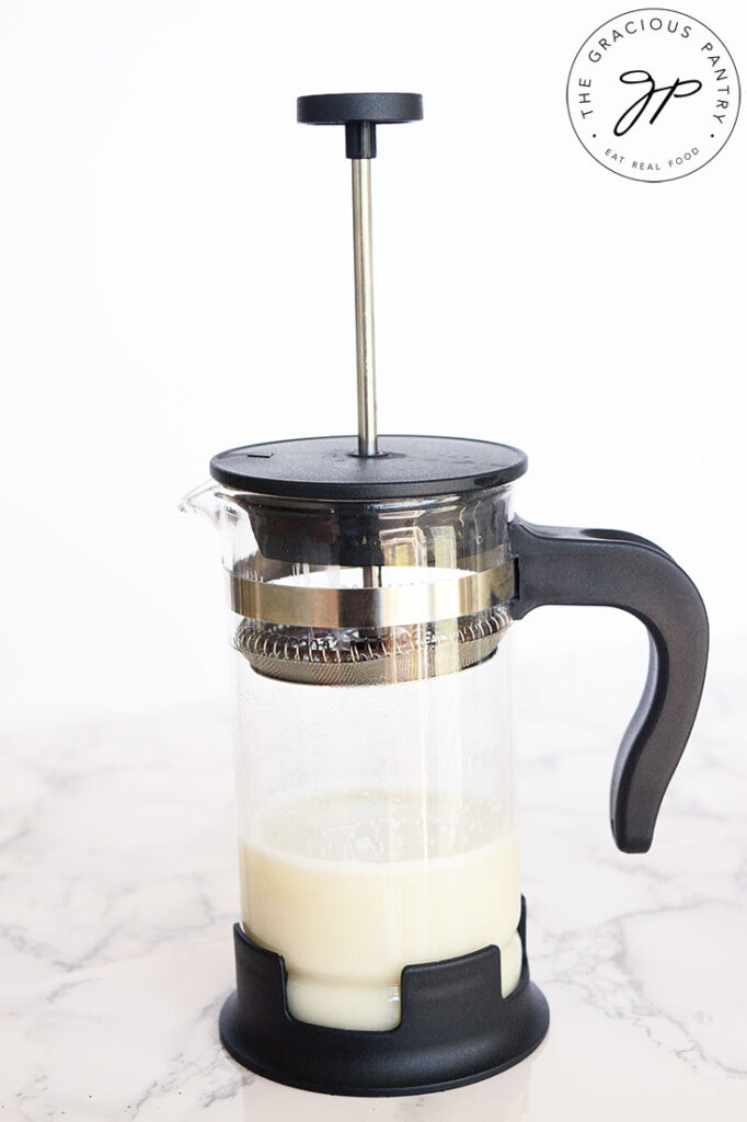 Milk in a french press ready to be frothed to make this London Fog Recipe.