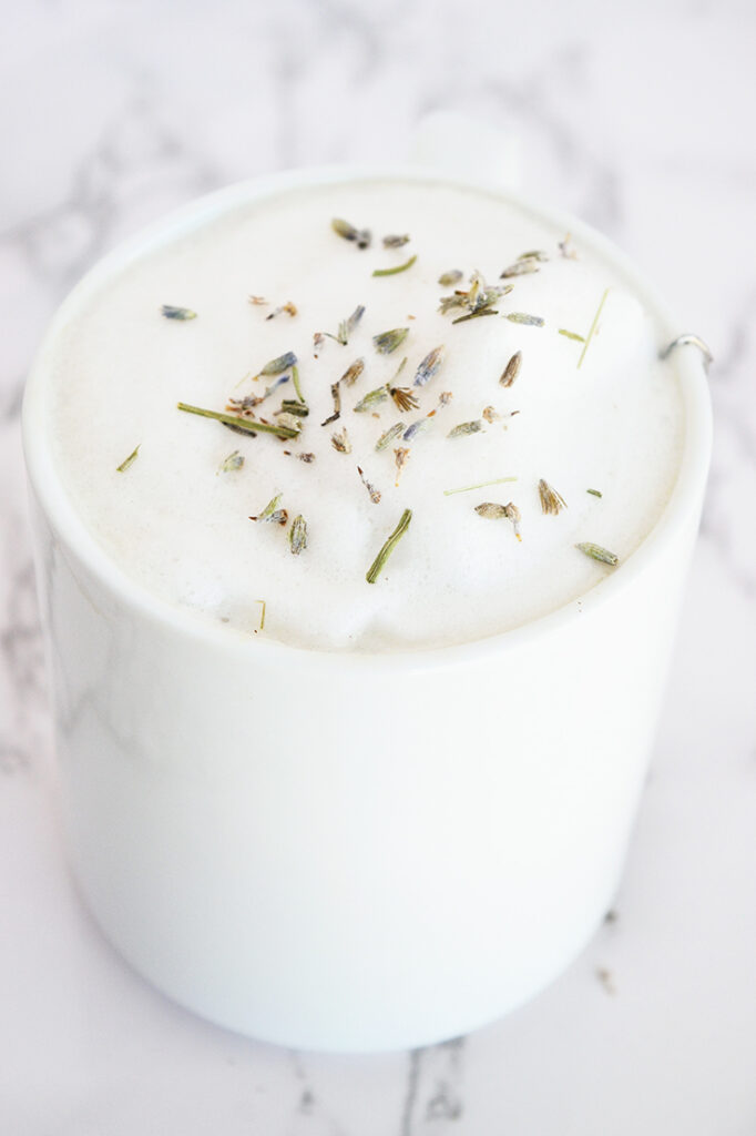 A side view of a white mug filled with this London Fog Recipe. Foamed milk sits at the top with dried lavender sprinkled over the top.