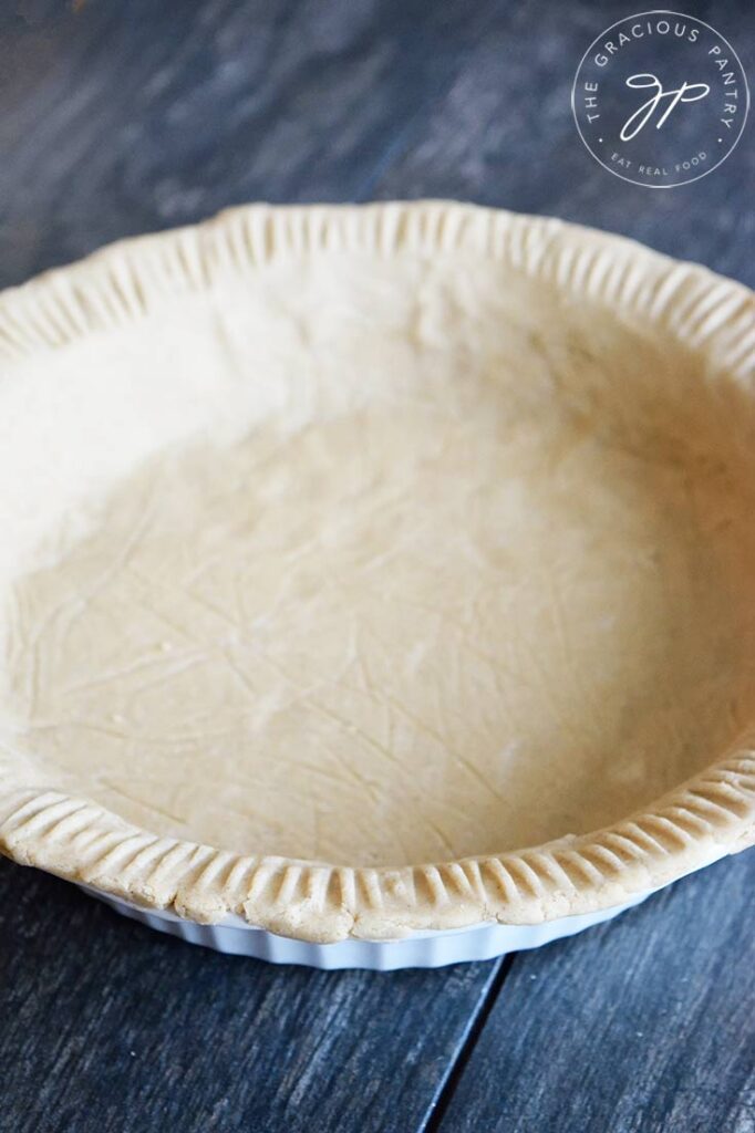 A side view of the finished oat flour pie crust in a white pie pan.