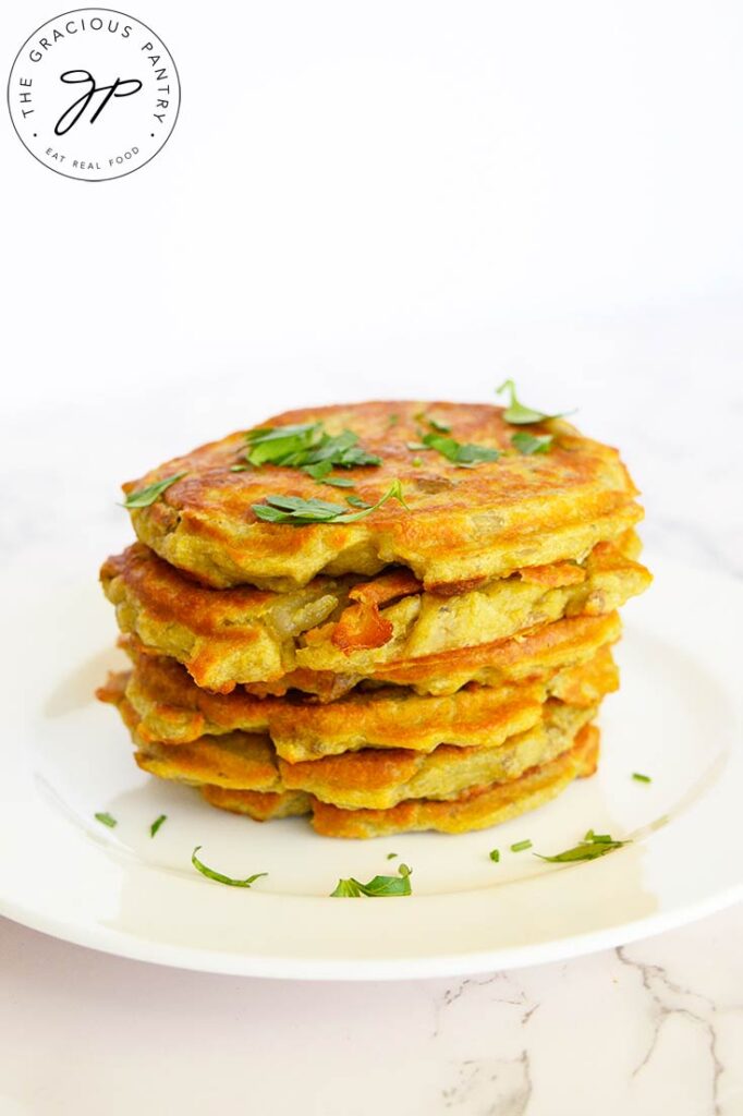 Side view of a stack of potato pancakes with fresh parsley for garnish.