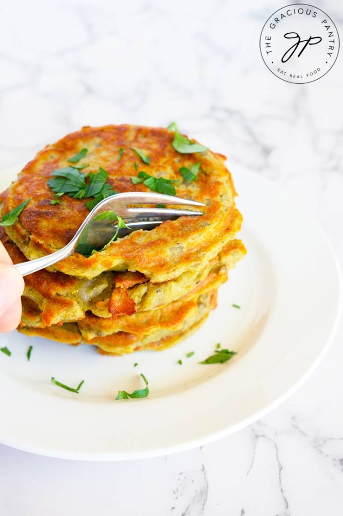 A fork pressing into these potato pancakes in this potato pancake recipe.