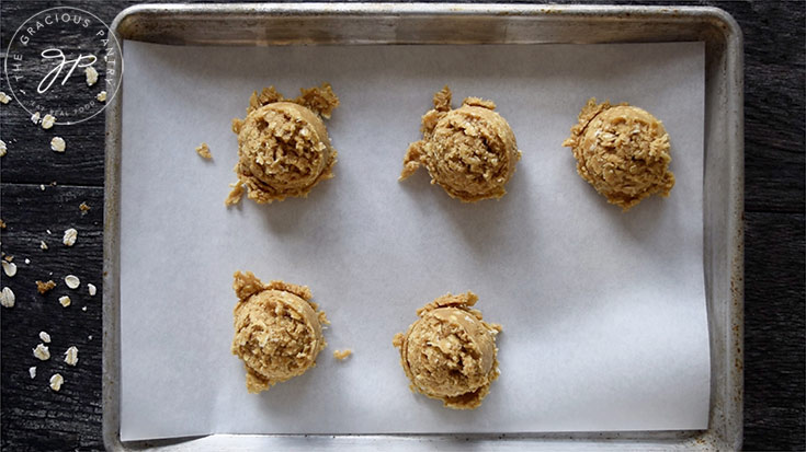 Scooped oatmeal cookie dough sitting on the cookie sheet