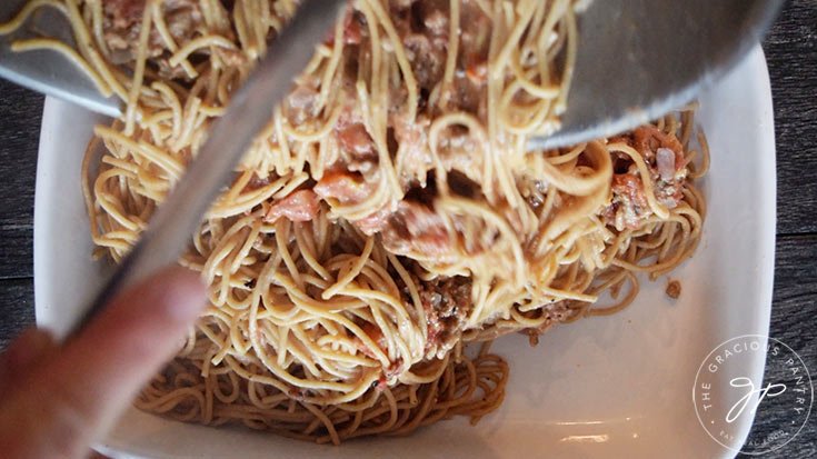 Transferring the pasta to the casserole dish for baking into spaghetti pie.