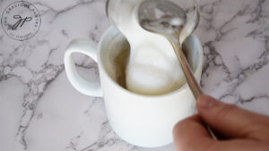 Pouring the frothed milk into the mug of tea.
