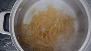 Adding the pasta to the water to boil