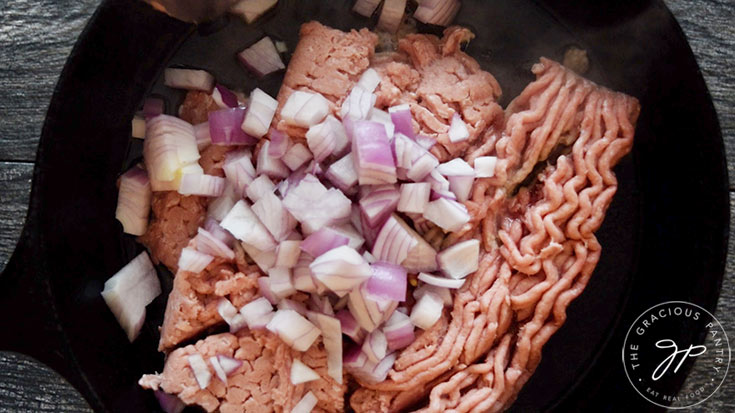 Adding chopped onions to the ground meat.