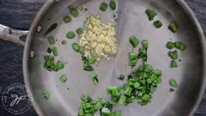 Adding minced garlic to the skillet.