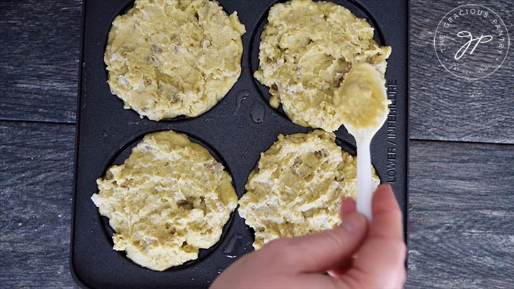 Spreading potato batter into pancakes on the pan.