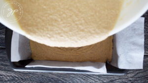 Pouring the first half of the batter into the loaf pan.