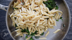 Adding cooked pasta to the skillet.