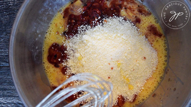 The grated parmesan added to the eggs and tomatoes in the mixing bowl.