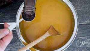 Stirring in the maple syrup into the pot of Bacon Sweet Potato Soup.