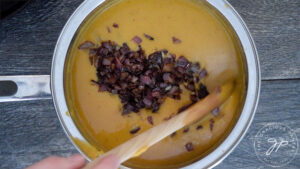 Stirring sautéd onions into the soup.