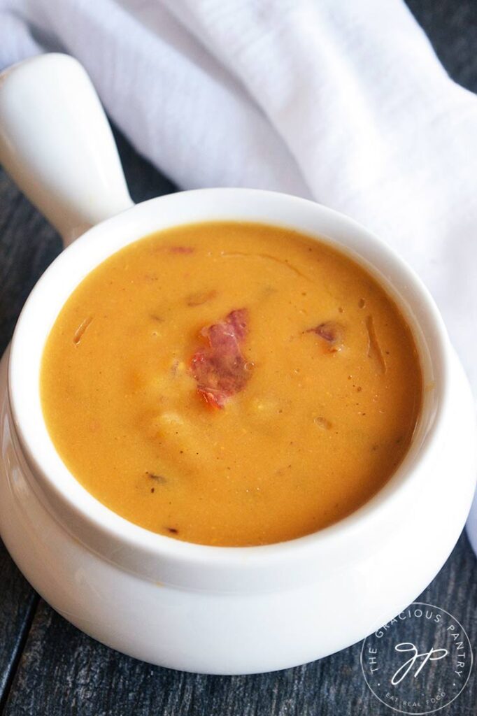 A closeup of a white crock filled with Bacon Sweet Potato Soup.