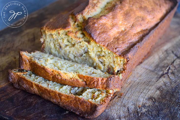 A horizontal shot of a loaf of oat flour banana bread with two slices cut off the front.