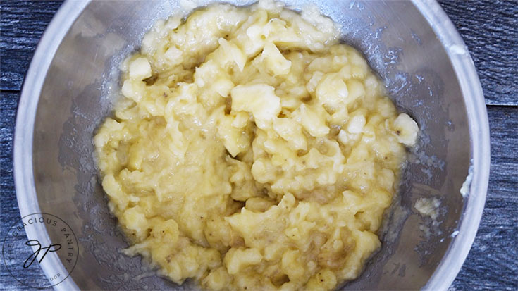 Step one of this Oat Flour Banana Bread recipe. The bananas mashed in a mixing bowl.