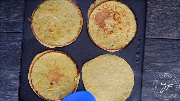 The pancakes cooking on the griddle.