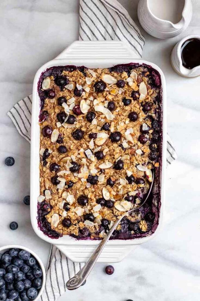 A white casserole dish sits on a table, filled with this blueberry baked oatmeal recipe.