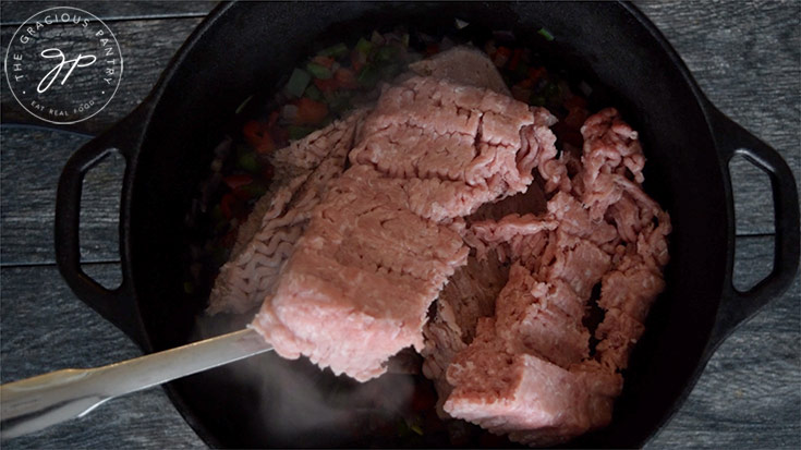 Adding ground meat to the dutch oven for this Dutch Oven Chili Recipe.