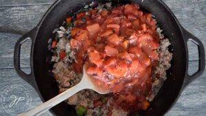 Stirring in the fire roasted, canned tomatoes for this Dutch Oven Chili Recipe.