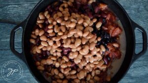 Adding canned pinto beans to the dutch oven for this Dutch Oven Chili Recipe