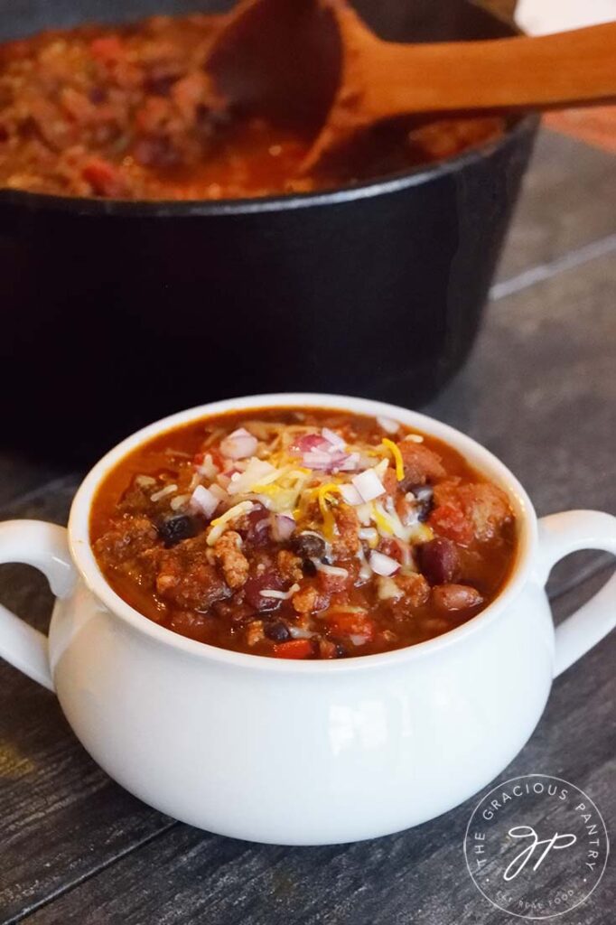 Dutch Oven Chili served in a white crock and topped with cheese.