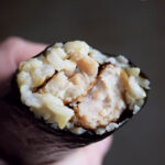 A roll of Gimbap with a bite taken off. You can see the sausage and rice inside the nori.